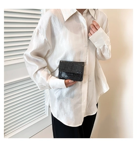 Détail d'un petit sac carré noir scintillant avec bandoulière chaîne sur modèle