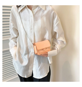 Vue détaillée du mini sac à bandoulière orange pêche brillant avec chaîne argentée