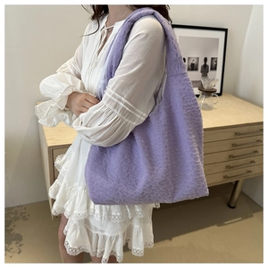 Detail of a purple textured lace hobo shoulder bag shown on model in a home setting
