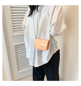 Détail du sac bandoulière orange nacré porté par un mannequin avec bandoulière
