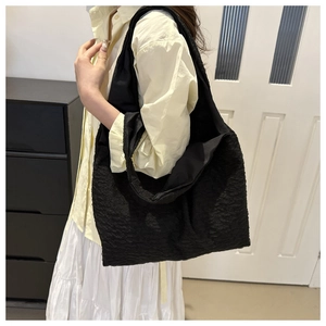 Detailed view of black pleated bubble texture fabric on a large shoulder tote bag