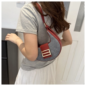 Detail of grey crescent underarm bag with red leather strap and gold metal buckle