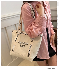 Detail view of large canvas tote bag with black letter print and sturdy shoulder straps