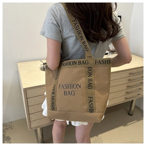 Detail of khaki canvas tote bag with FASHION BAG lettering and reinforced shoulder strap