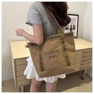 Detail of khaki canvas tote bag with black FASHION BAG print and wide shoulder strap
