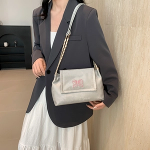 Silver shoulder bag with pink butterfly embroidery and chain strap worn by a model