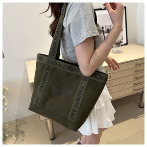 Shoulder view of olive green canvas tote bag with fashion lettering and large capacity