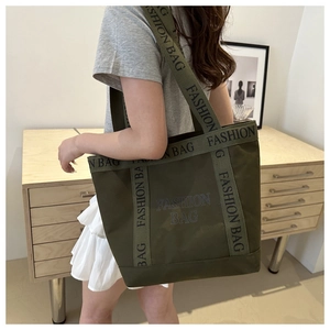 Detail view of olive green tote bag with wide fashion strap and letter print