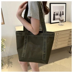 Detail of army green canvas tote bag with fashion bag text strap on model shoulder