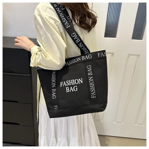 Close-up of black canvas tote bag showing the bold white FASHION BAG letter printing