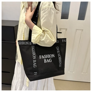 Gros plan sur le sac fourre-tout en toile noire avec lettrage blanc FASHION BAG