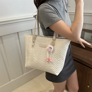 Chic beige quilted tote bag with V-shaped stitching and plush charm for daily commute
