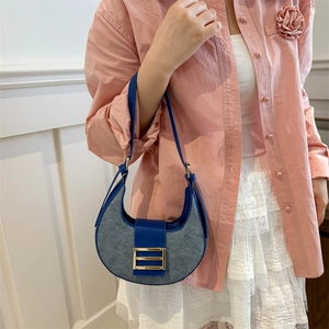Retro grey and navy blue crescent shoulder bag with gold buckle on a model