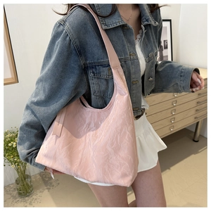 Vue détaillée de la texture froissée rose brillant sur ce grand sac hobo porté épaule