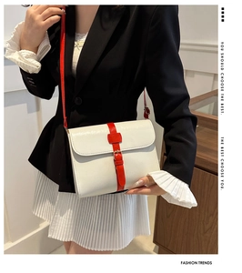 Détail du sac à rabat blanc avec bandoulière en cuir rouge et boucle en métal doré