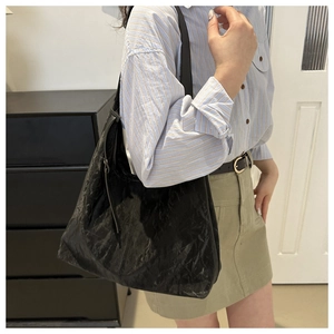Détail du sac bandoulière en cuir plissé noir montrant la texture et le design demi-lune