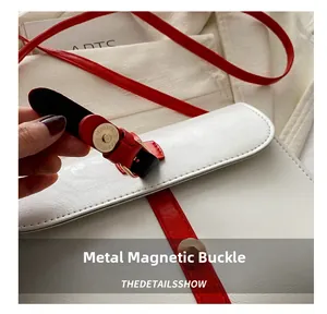 Gros plan du fermoir magnétique en métal et du grain du cuir sur un sac à bandoulière blanc
