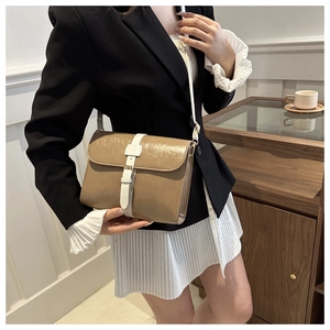 Sac bandoulière carré marron et blanc porté dans un décor de style minimaliste