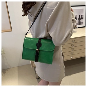 Détail d'un sac bandoulière vintage vert vif en cuir avec boucle noire et sangle décorative