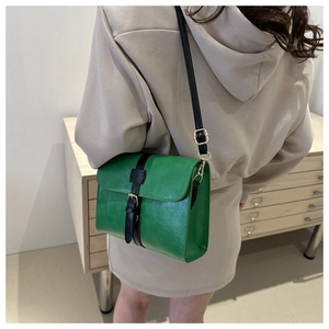 Vue détaillée d'un sac bandoulière vintage vert avec boucle dorée porté par un modèle