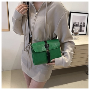 Détail du sac bandoulière carré vert vif avec sangle en cuir noir et boucle dorée