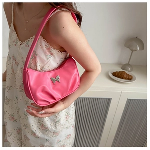 Sac hobo rose avec papillon argenté porté sur une robe d'été à fleurs blanches