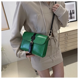 Détail du sac bandoulière carré vert avec sangle décorative noire et boucles dorées