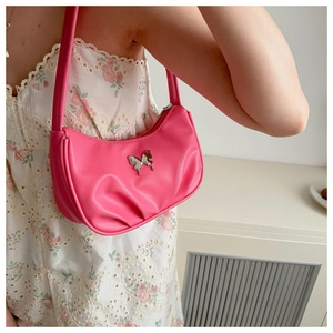 Détail d'un sac porté épaule rose plissé avec une boucle papillon argentée et robe florale