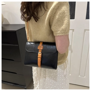 Vue latérale d'un sac bandoulière vintage en cuir porté par un mannequin dans un salon
