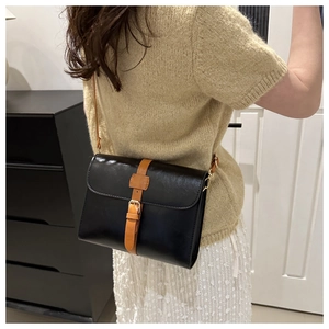 Détail du sac bandoulière vintage en cuir noir brillant avec boucle marron classique