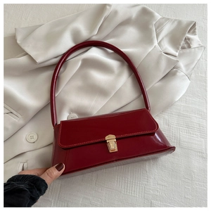 Détail du sac baguette en cuir verni bordeaux avec un fermoir en métal doré vintage