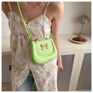 Detail of lime green mini saddle bag with golden butterfly buckle worn by a model