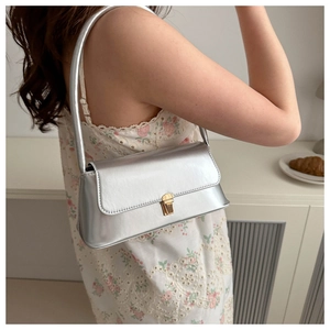 Sac sous le bras en cuir verni argenté avec boucle dorée porté par un mannequin
