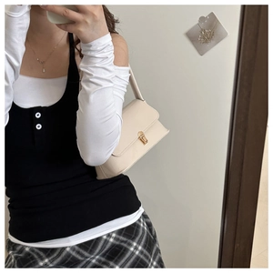 Selfie montrant un sac baguette crème avec fermoir doré porté à l'épaule par une femme