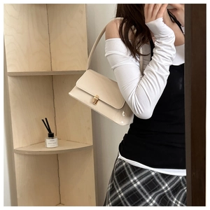 Détail d'un sac baguette blanc crème avec finition brillante et boucle dorée chic