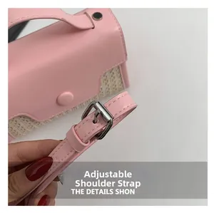 Detail of adjustable pink leather shoulder strap with silver buckle on woven handbag