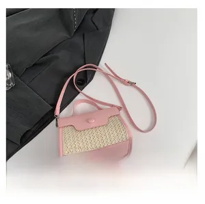 Detail of pink leather and woven straw crossbody bag with round handle and strap