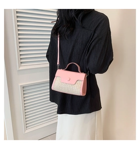 Pink leather and straw texture small square bag worn by a model in a bright setting