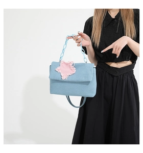 Detail of Y2K denim handbag featuring pink star patch and light blue chunky chain strap