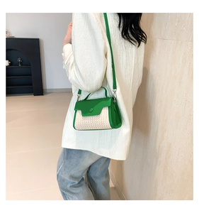 Detailed shot of a green straw patchwork crossbody bag worn by a model in a modern interior