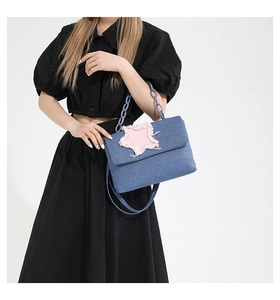 Close-up of denim shoulder bag featuring a pink frayed star patch and thick chain handle
