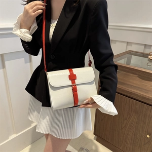 Sac bandoulière carré blanc et rouge porté par un mannequin dans une tenue élégante