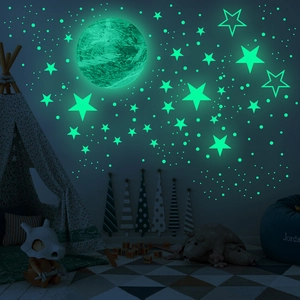 Luminous moon and star wall stickers glowing green in a dark children's room scene