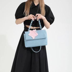 Blue denim crossbody bag with pink star patch and plastic chain strap shown on model