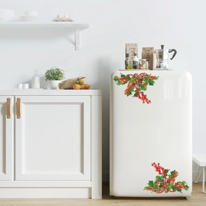 Close-up of Christmas stickers with holly leaves and red berries on a white fridge