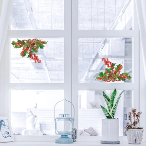 Close-up of Christmas window stickers with holly leaves, red berries and pine cones decor