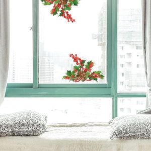 Detail of Christmas window stickers with festive holly leaves, red berries and pine cones