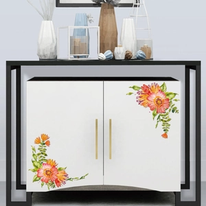 Close-up of watercolor floral stickers with orange flowers and green leaves on a white cabinet