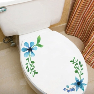Close-up of watercolor blue floral stickers applied to a white ceramic toilet lid