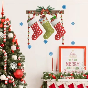Trois chaussettes de Noël suspendues à un mât en bois avec perles sur un mur blanc